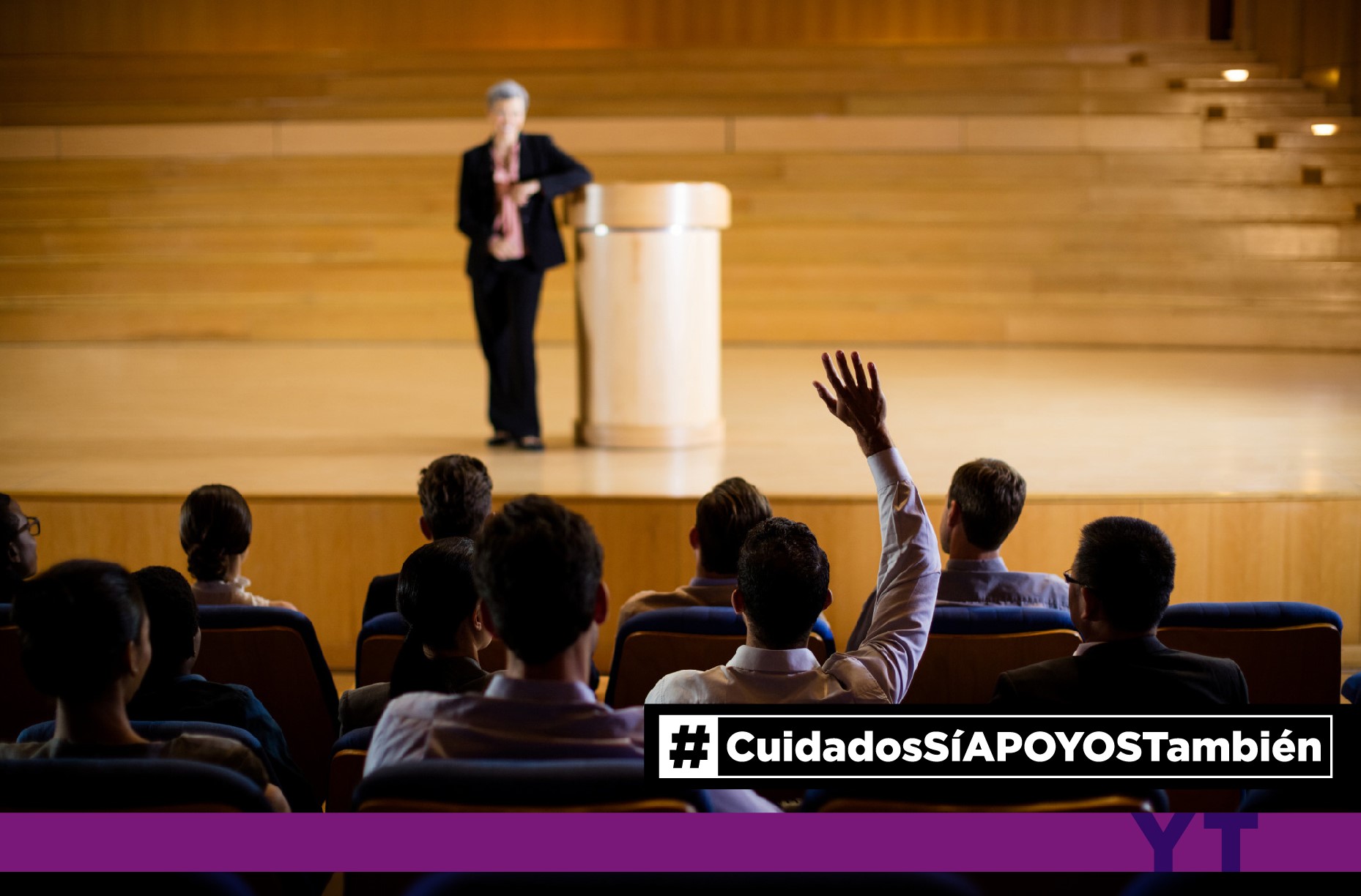 Persona en un escenario hablando frente a un auditorio